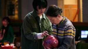 A younger woman helping an older woman with a bowling ball for the new film Plan 75