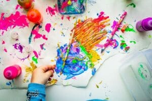 Paint drawings on paper and a child's hand for Summer Holidays Events in Kent 2023