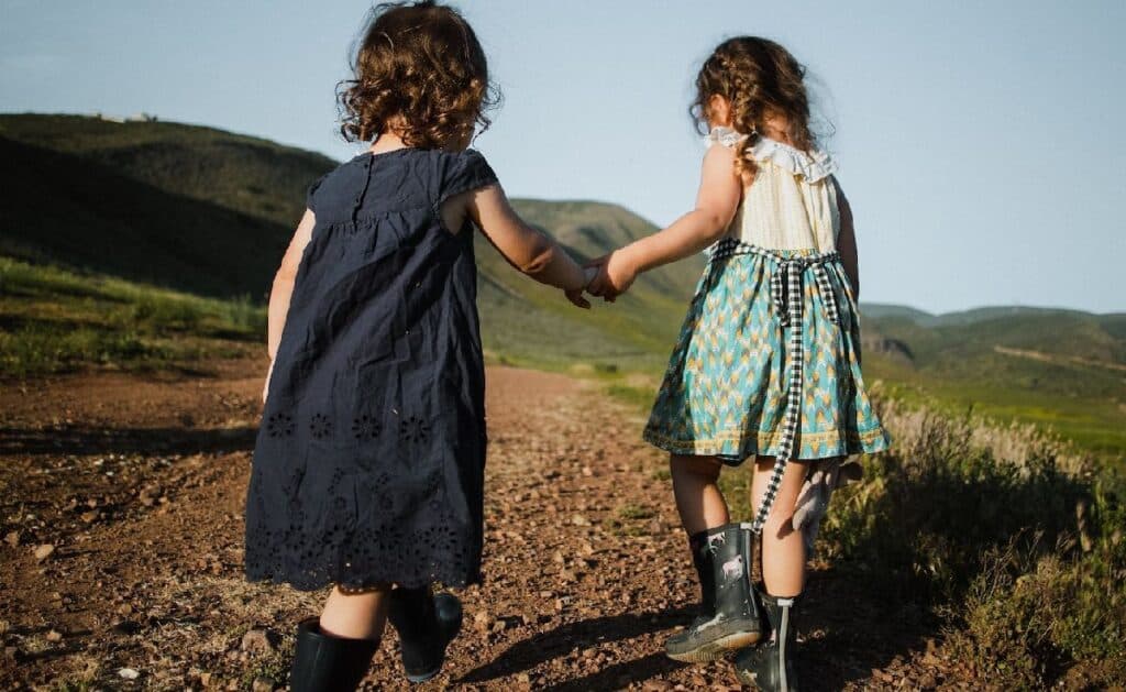 The back of two young girls in dresses holding hands for Summer Trails 2023 blog post